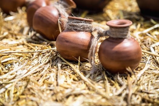 Small ceramic crocks or pot countryside decoration or souvenir on straw. Selective focus of image on one of crock
