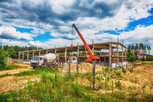 Building under construction at a construction site with crane and concrete mixer. Processed by hdr effect filter