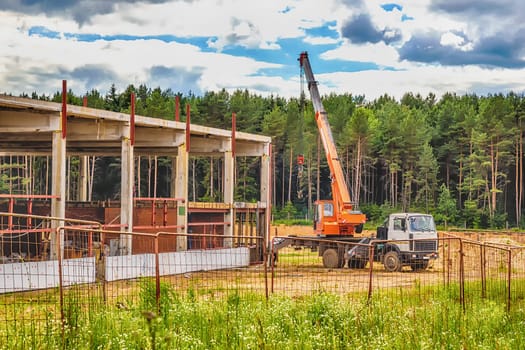 Building under construction at a construction site with a truck and a crane. Processed by hdr effect filter