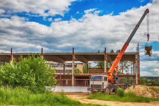 Building under construction at a construction site with a truck and a crane. Processed by hdr effect filter