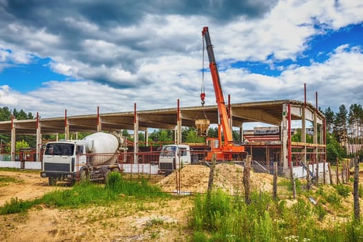 Building under construction at a construction site with crane and concrete mixer. Processed by hdr effect filter