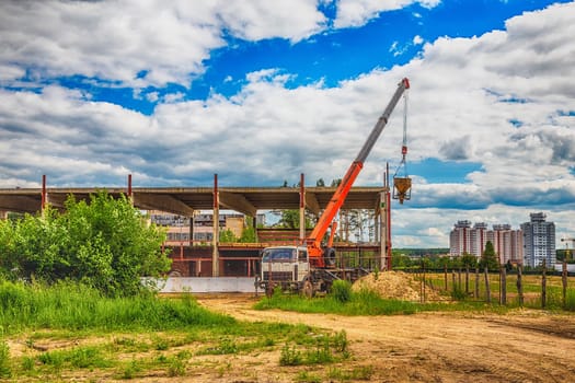 Building under construction at a construction site with a truck and a crane. Processed by hdr effect filter