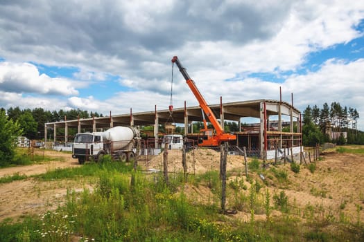 Building under construction at a construction site with crane and concrete mixer