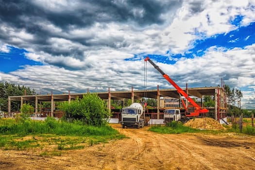 Building under construction at a construction site with a truck and a crane. Processed by hdr effect filter