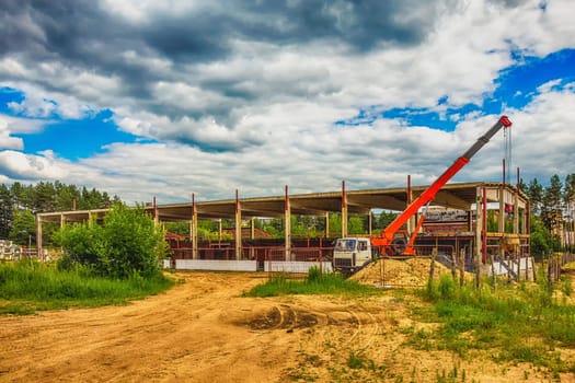 Building under construction at a construction site with a truck and a crane. Processed by hdr effect filter