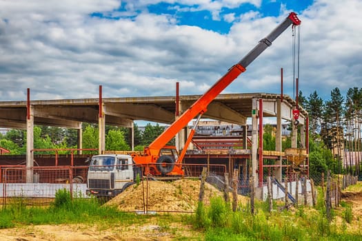 Building under construction at a construction site with a truck and a crane. Processed by hdr effect filter