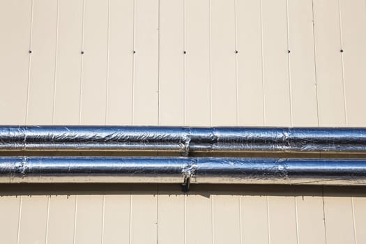 Metal chrome pipes on yellow plastic siding wall