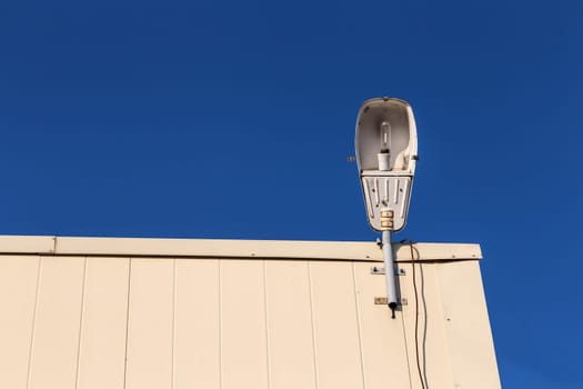 Old vintage lamp on rooftop against blue sky background