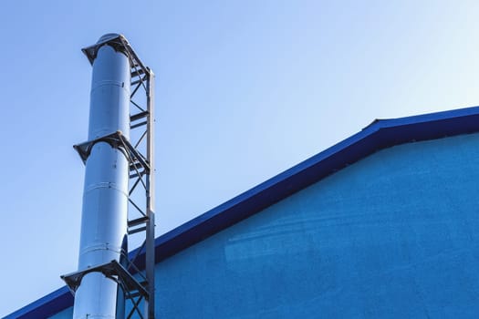 Smoke metal chrome pipe on rooftop  against blue sky background