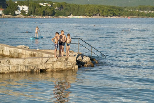 Fishing and bathing children on the coast of the town Krk on the Adriatic Sea in Croatia