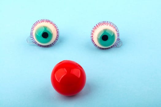 Decorative fruit candy eyes with red nose over light blue background. Conceptual photo using for funny celebration themes.
