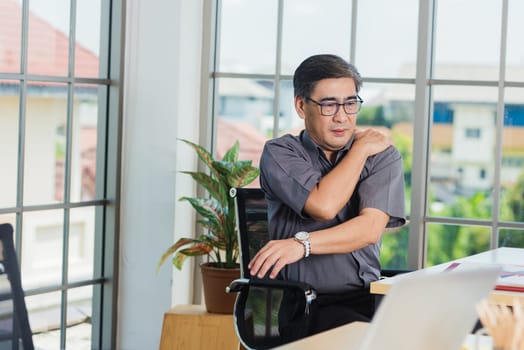 Asian hard senior businessman working with laptop computer has a problem with shoulder pain. Old man feeling pain after sitting at desk long time, Healthcare and medicine office syndrome concept