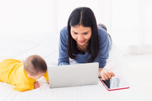 Asian new young beautiful mother finding and reads information on a laptop for milk mixing on a bottle in the bedroom at home