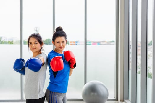 Asian lifestyle adult and young woman smiling sports fitness boxer wearing gloves practicing kick on boxing in sportswear work out indoor yoga studio, sport healthy workout concept