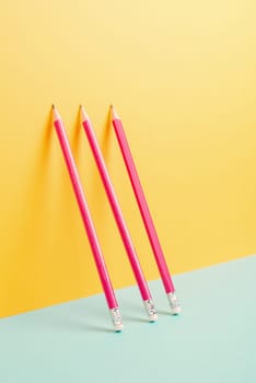 Pink pencils on a yellow and blue background, minimalism, creative, surreal and education concept, copy space for text, pastel colored wall