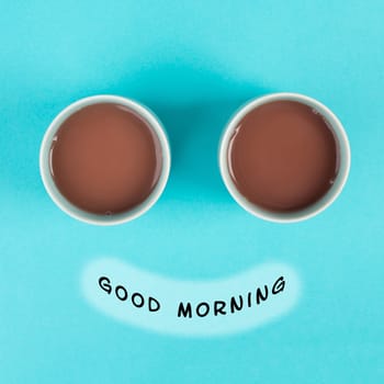 Cup of coffee building the eyes of the funny face, mouth with the phrase good morning, wake up in the morning, hot drink with caffeine