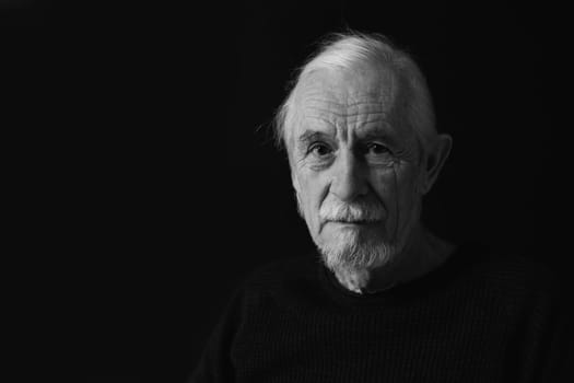 Low key studio black and white front view of beautiful gray hair old man.