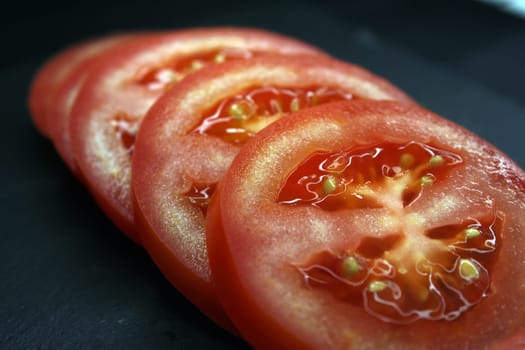 Tomato slices on a black background close-up. The concept of healthy eating..