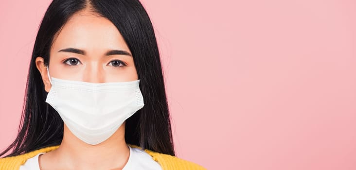 Closeup face Asian beautiful young woman wearing medical mask protection against germs for prevent infection coronavirus, COVID-19, studio shot isolated on pink background, medical health care concept