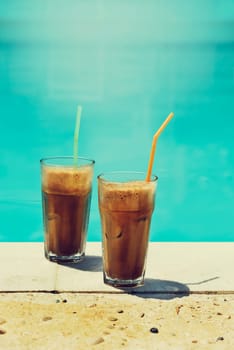 Two glass of iced frappe near the swimming pool. Retro filter image