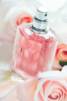 Luxury perfume bottle with pink roses petals. Fashion makeup and body care products.