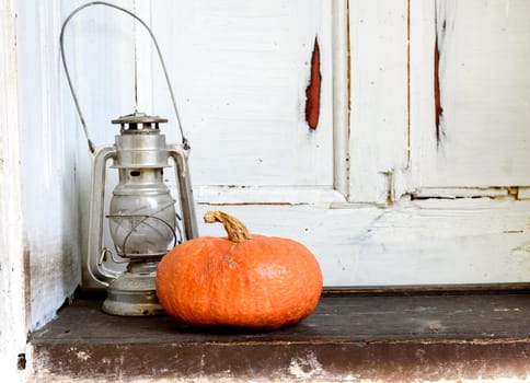 Halloween pumpkin and old lantern on the grunge wooden background. Autumn concept still life.
