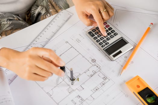 Architectural project workplace. Architect drawing with divider compass on house plan blueprint paper for repair tools on table desk at architecture office, Engineer sketching construction project