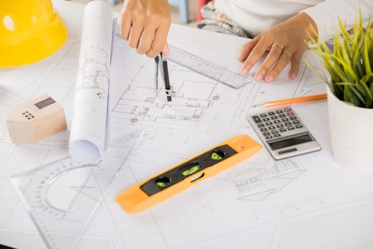 Architectural project workplace. Engineer sketching construction project, Architect drawing with divider compass on house plan blueprint paper for repair tools on table desk at architecture office
