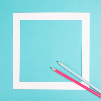 Pencils on a blue paper background, white frame with copy space for text, minimalism, creative and business concept, pastel colored