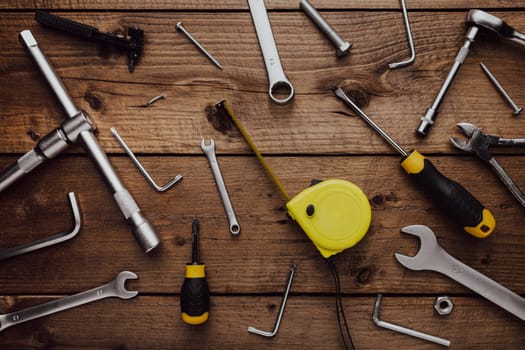 Flat lay with DYI composition of various work, carpentry tools knolled on brown wooden decks background pattern working table. Top view on new hand tool set for repair and construction kit, overhead