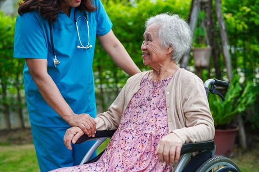 Doctor help Asian elderly woman disability patient sitting on wheelchair in park, medical concept.