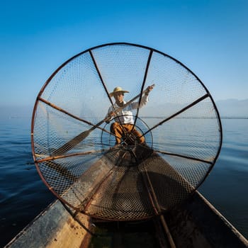Myanmar travel attraction landmark - Traditional Burmese fisherman with fishing net at Inle lake in Myanmar famous for their distinctive one legged rowing style