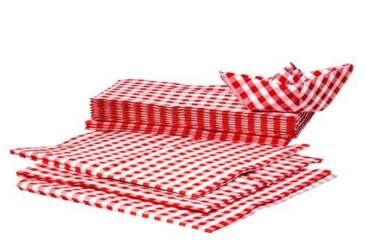 Closeup of a stack of red checked paper napkins and a folded paper ship isolated on a white background. Clipping path. Macro. Stacked towel or tablecloth.
