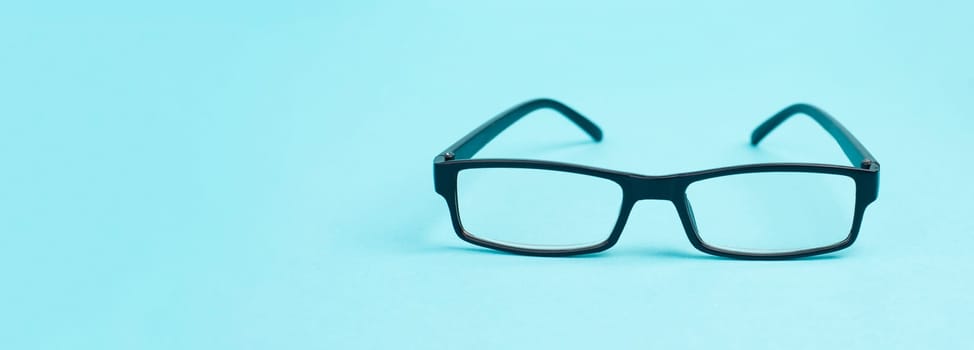 Glasses with a black frame on a blue background, copy space for text