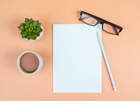 Empty paper with a pen, cup of coffee, eyeglasses and a cactus, brainstorming for new ideas, writing a message, taking a break, home office desk