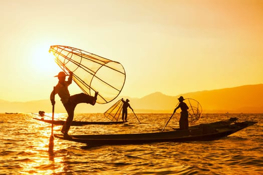 Vintage retro effect filtered hipster style image of Myanmar travel attraction. Traditional Burmese fisherman with fishing net at Inle lake famous for their distinctive one legged rowing style
