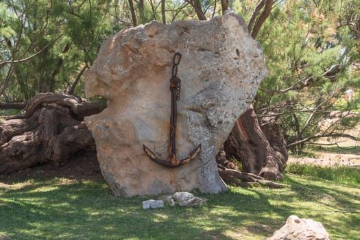 Old rusted ship anchor hanging on a stone in Majorca, Spain.