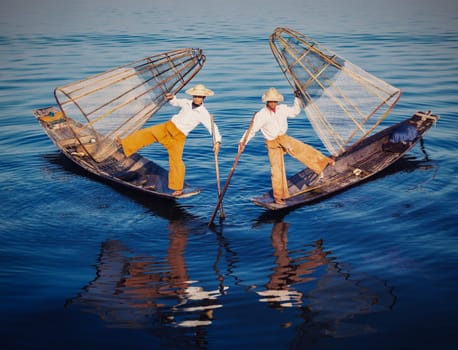 Myanmar travel attraction - Traditional Burmese fishermen balancing with fishing nets at Inle lake in Myanmar. Vintage filtered retro effect hipster style image