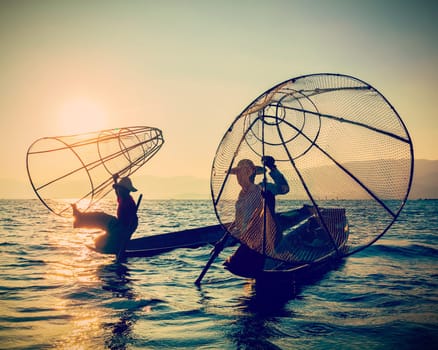 Myanmar travel toursist attraction landmark - two traditional Burmese fishermen at Inle lake, Myanmar on sunrise. Vintage filtered retro effect hipster style image