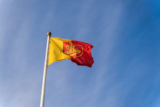 Flag and coat of arms of the city of Klaipeda on the background of the blue sky.