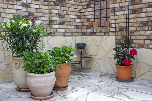 beautiful place in the garden in the mediterranean style, brick wall and pots with flowers