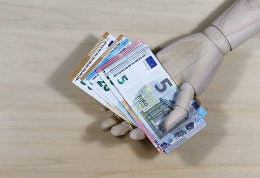 Give away money. A wooden hand and euro bills