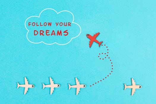Red airplanes takes a different direction, flying to the cloud with the phrase follow your dreams, motivation and coaching concept, positive thinking, having a goal, mindset of freedom