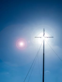 The radio mast obscuring the sun in the outshined backlight and lens flares in a blue sky in Carolinensiel East Frisia.
