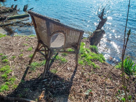 High angle view of a wicker chair on the shore of the Lake Flaken near Wolterddorf in Brandenburg in April 2022.