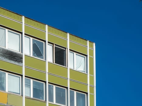 Teilansicht einer dachnahen Ecke eines Bürohausen mit defekter Fensterscheibe vor blauem Himmel.