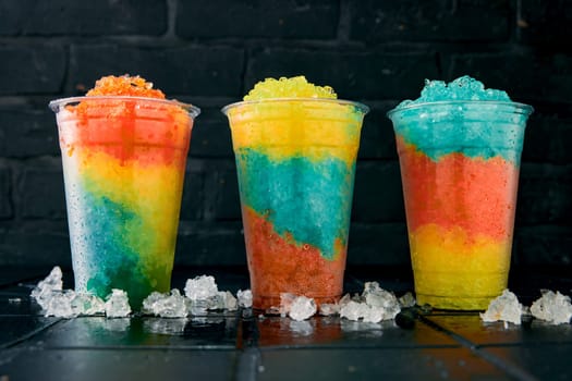 Glasses full of tasty slush drinks in a row on black background.