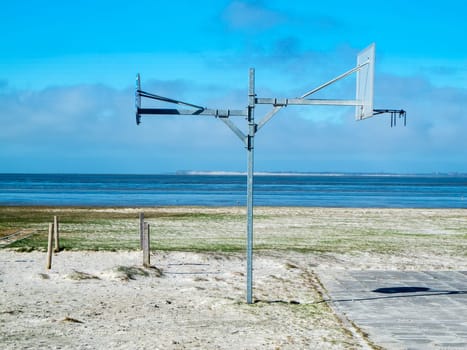 Side view of a double-sided street basketball hoop mast on the North Sea beach in Harlesiel Ostfriesland in front of a blue sky.