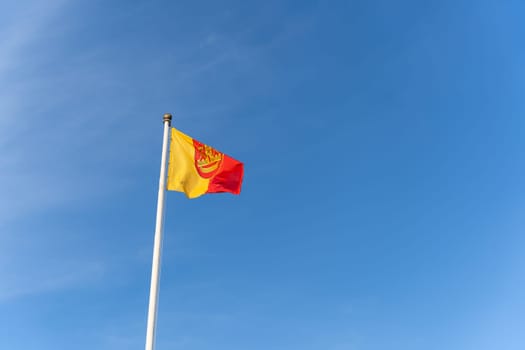 The flag of the Lithuanian port city of Klaipeda flies against the background of a blue clear cloudless sky.