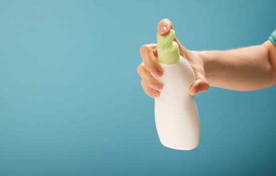 Unrecognizable female pressing dispenser on bottle of soap during hygienic routine against turquoise background